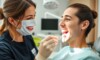 Dentiste souriant examine les dents d'un patient.